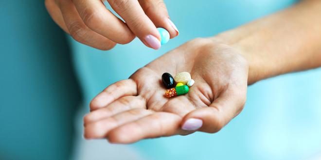 a woman with a few colorful vitamin capsules in her hand